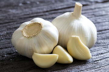 Raw Garlic Bulb and Cloves on dark wooden background