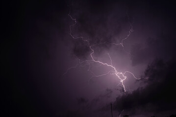 A bright flash of lightning against the dark purple night storm sky>