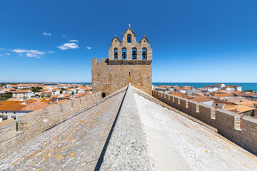Symmetrical wide angle view of the rooftop of the french church of Saintes Maries de la Mer, against a blue summer sky © Roberto
