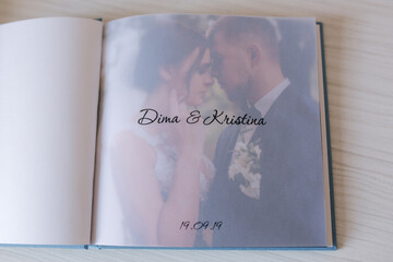 Open photobook with tracing paper with groom and bride on white wooden table