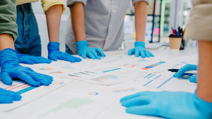 Asia businesspeople discussing business brainstorm meeting together share data, wearing face mask and glove back at work in new normal office. Lifestyle and social distancing at after coronavirus.