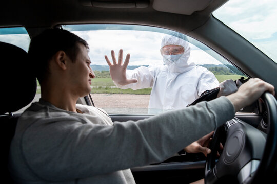 Ban movement of cars on border of cities due to pandemic coronavirus COVID 19 or Bubonic Plague, man in biological protective suit shows stop gesture