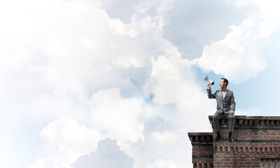 Businessman or manager on building roof announcing something in loudspeaker