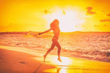 Happy free sexy woman silhouette running with scarf flying in the wind at sunset glow for weight loss happiness concept. Sun vacation travel beach.