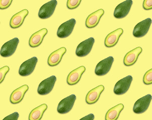 Naklejka premium Pattern of whole and halved avocados on pale yellow background