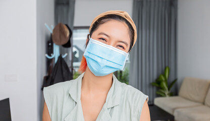 Asian woman smiling behind the mask have a happy face In her house for social distancing concept.