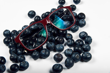 Freshly juicy picked blueberries and eyeglasses isolated on white background. 