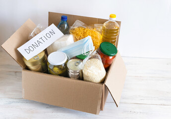 Cardboard box with oil, canned food, cereals and pasta.