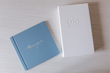 Comparison of photobook and photo box. Blue wedding book and white photo box on white wooden table