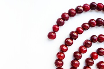 Red cherry ripe juicy is laid out in a spiral on a white background.