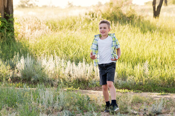 Emotional portrait of a happy and cheerful little boy, running and playing on a walk in the park. Happy childhood. Summertime. Summer vacation. Positive emotions and energy