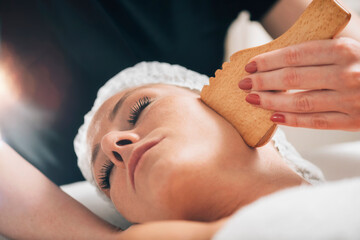 Obraz na płótnie Canvas Face Massage with Wooden Gua Sha Plate Shape Massager