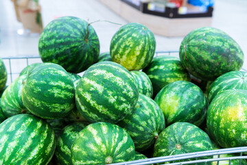 Watermelons on supermarket shelf. Summer Fruits. Fresh organic water melon fruit for sale in grocery store.