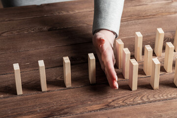 Businesswoman protecting dominoes from falling