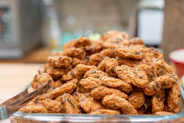 close up to pile of Thai fried fish paste meat balls in glass triangle dish.