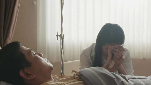 Asian patient man ill on bed in recovery room at hospital, wife crying