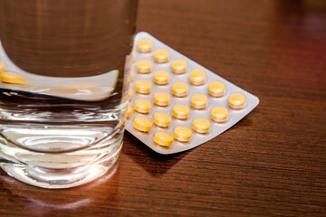 A package of orange tablets is placed on a brown background
