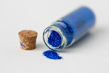 party, decoration and holidays concept - close up of ultramarine blue glitters poured from small...