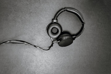 Black headphones on black matte background. Minimalistic composition top view.