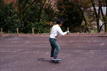 Fototapeta premium 公園の駐車場でキャスターボードで遊ぶ男の子
