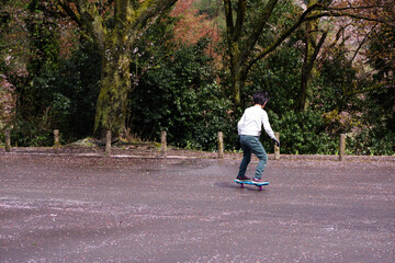 Fototapeta premium 公園の駐車場でキャスターボードで遊ぶ男の子