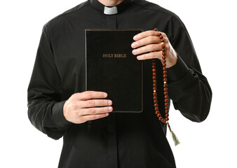 Handsome priest with Bible and rosary beads on white background