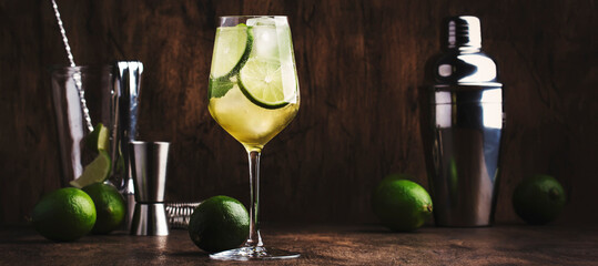 Mojito cocktail with lime and mint in wine glass on wooden background. Panoramic banner with copy...
