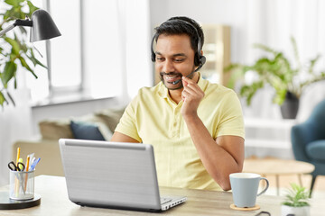 remote job, technology and people concept - happy smiling indian man with headset and laptop...