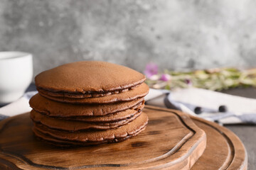 Board with delicious chocolate pancakes on table