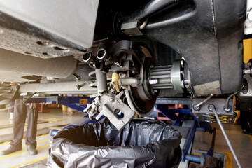 A mechanic repairing, grinding the brake disc and replacing worn out brake pads at an auto repair shop service station - vehicle safety concept