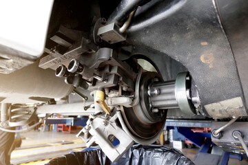 A mechanic repairing, grinding the brake disc and replacing worn out brake pads at an auto repair shop service station - vehicle safety concept