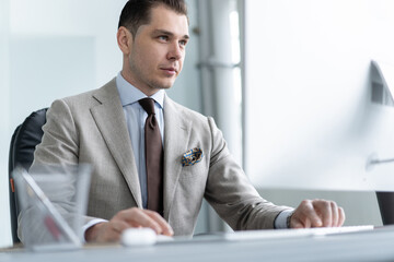 Fototapeta premium Young employee looking at computer monitor during working day in office