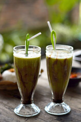 2 Fresh avocado juice in a glass with the addition of liquid chocolate milk and plastic straws