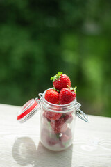 Fresh strawberries in a can in nature on a white wooden window sill.