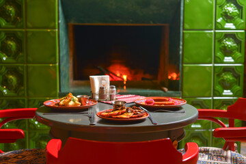 Ukrainian dinner setup, red and green decoration, traditional fireplace. Interior design.