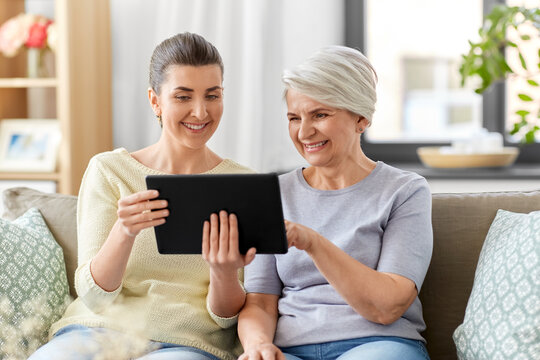 Family, Generation And Technology Concept - Happy Smiling Senior Mother And Adult Daughter With Tablet Pc Computer At Home