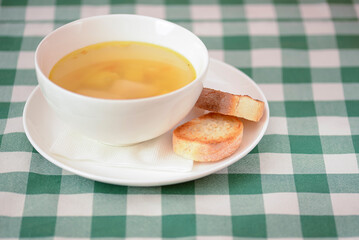 Chicken soup with vegetables and meat served in a white bowl over rustic wooden background with...