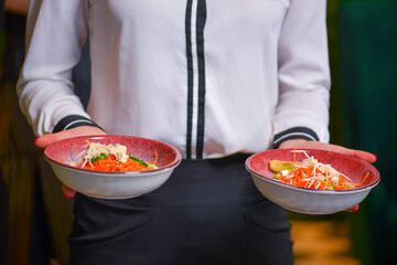 Waiter serving two plates of healthy green salad. Two plates of vegetable salad with feta cheese.