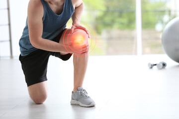 Man in suffering from knee pain at gym, closeup