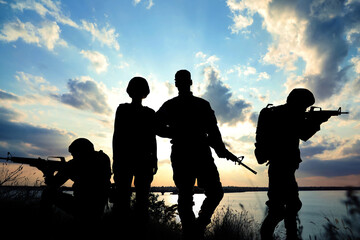 Fototapeta na wymiar Silhouettes of soldiers with assault rifles patrolling outdoors. Military service