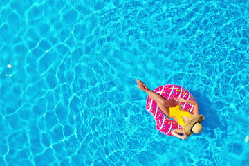 Young woman with inflatable ring in swimming pool, top view. Space for text