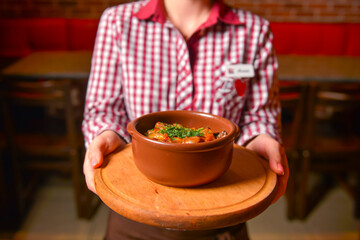 Traditional hot goulash soup. Waiter serving vegetable stew in a pot. Concept for a tasty meal....