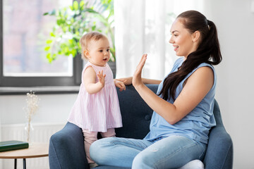 family, child and motherhood concept - portrait of happy smiling mother with little baby daughter playing clapping game at home