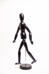 black wooden doll in a walking pose on a white background