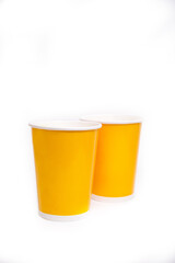 two yellow paper cups stand side by side on a white background