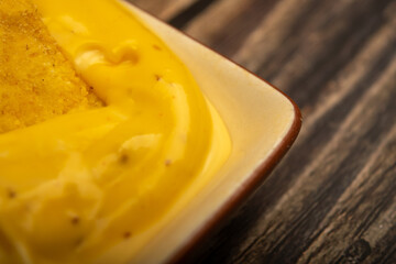 Corn chips with cheese sauce on a wooden background. Close up.