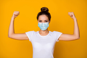 Close-up portrait of her she nice attractive pretty girl wearing safety gauze mask demonstrating biceps muscles stop viral pneumonia mers cov influenza isolated vibrant yellow color background