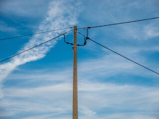 High voltage tower in a village, under a blue sky