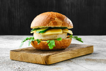 Homemade fishburger with cheese, arugula and cucumber