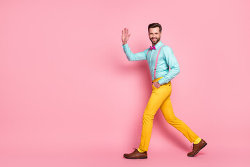 Fototapeta na wymiar Full size profile photo of handsome guy trend stylish look walk red carpet celebrity waving hand wear shirt suspenders bow tie yellow pants footwear isolated pastel pink color background